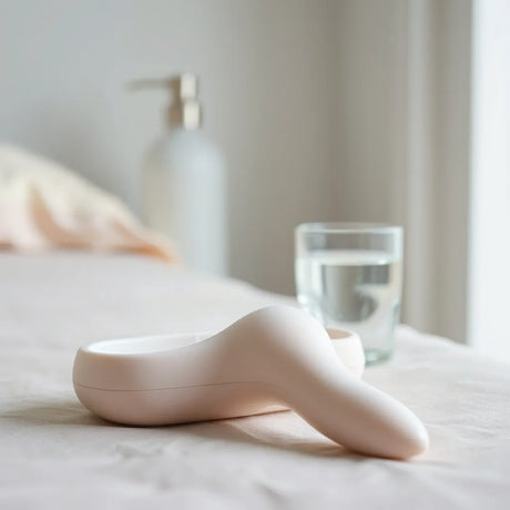 Smooth silicone sex toy on a clean surface with soft lighting and a minimal storage case nearby